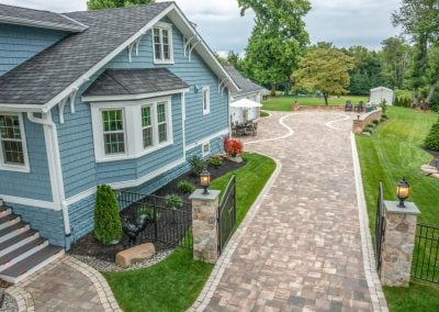 A paved driveway leads to a blue house with white trim in Aberdeen, surrounded by green lawn and beautiful landscaping.