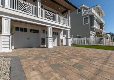 A paved driveway leads to a white garage of a modern two-story house with a fenced yard in Aberdeen, MD—crafted by Solid Brick Contracting.