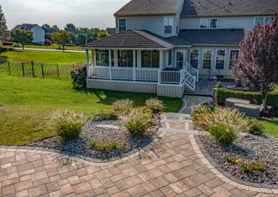 Backyard with a paved patio, expert landscaping, stone pathway, and a screened porch—beautifully crafted by Solid Brick Contracting.