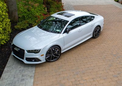 A white Audi sedan parked on a paved driveway, surrounded by lush landscaping and trees, creates a serene retreat in Aberdeen.