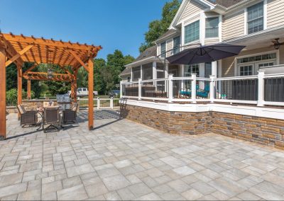 Spacious backyard patio in Aberdeen, MD, featuring a pergola, dining set, umbrella, and raised porch—expertly crafted by Solid Brick Contracting.