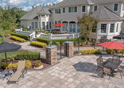 Spacious backyard patio in Aberdeen with lounge chairs, dining table, umbrellas, and professional landscaping by Solid Brick Contracting near a large house.