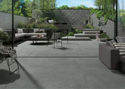 Modern outdoor patio by Solid Brick Contracting features gray tiles, stylish sofas and chairs, lush greenery, hardscaping elements, and a striking tiered stone garden wall—perfect for Aberdeen-inspired outdoor living.