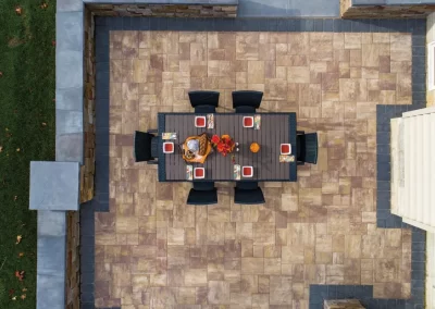 Aerial view of a patio with a rectangular dining table set for six, surrounded by expertly crafted stone tiles—an example of thoughtful hardscaping by Solid Brick Contracting in MD.