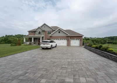 Large brick house in Aberdeen with attached garages, SUV parked on wide paved driveway, and lush landscaping surrounding the green lawn.