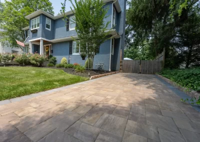 A paved driveway leads to a blue two-story house in Aberdeen, featuring pristine landscaping and a well-kept lawn and garden.