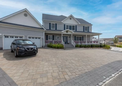 Two-story house in Aberdeen with a large driveway, attractive landscaping, a parked black car, and patriotic bunting on the porch railing—expertly updated by Solid Brick Contracting.