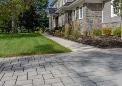 Gray paver driveway leading to a large house with stone accents and manicured landscaping in Aberdeen, MD.