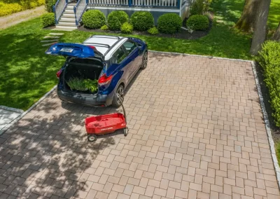 A blue SUV with its trunk open is parked on a hardscaping driveway in MD, next to a red wagon.