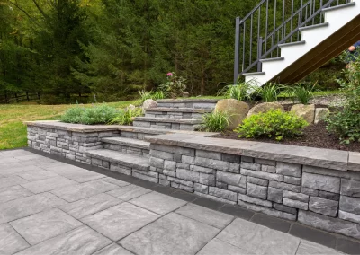 Stone steps and a retaining wall with landscaped plants line the backyard staircase, expertly crafted by Solid Brick Contracting. Enhance your MD garden with professional landscaping and timeless design.