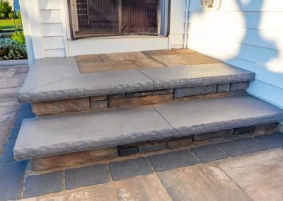 Stone steps with a concrete finish, crafted as part of expert hardscaping, lead to the doorway of a white house in Aberdeen, seen in daylight.