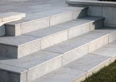 Wide, gray stone steps lead up to a patio; grass and a planted area—expertly shaped by Solid Brick Contracting's landscaping team in Aberdeen—are visible on the right side.